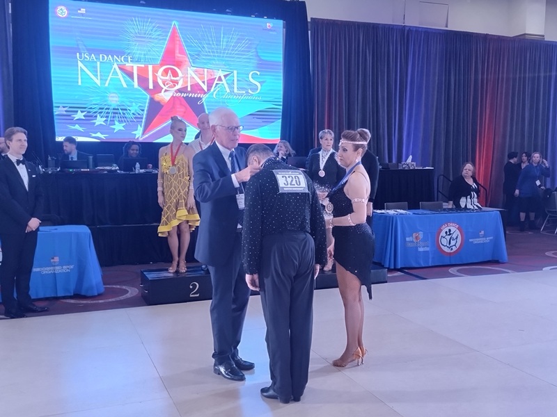 Denis Kojinov and Jeanette Chevalier receiving gold medal at 2025 USA Dance Nationals in 10-dance category